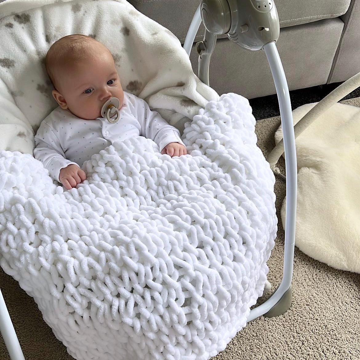 Baby in a white hand knitted baby blanket