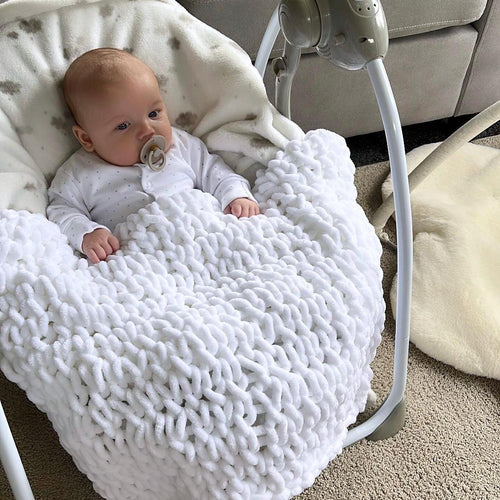 Baby in a white hand knitted baby blanket